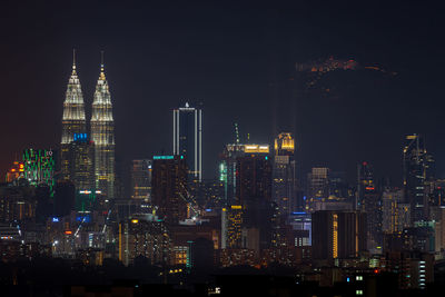 Illuminated buildings in city against sky at night