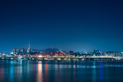 Illuminated buildings by hanriver against blue sky at night in korea