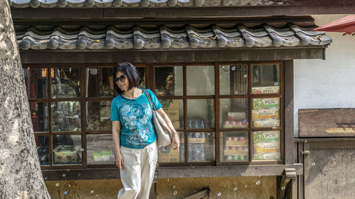 Full length of woman standing outside house