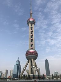 Communications tower in city against sky