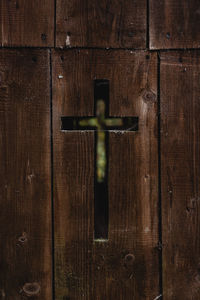 Close-up of a cross shape carved in wooden door