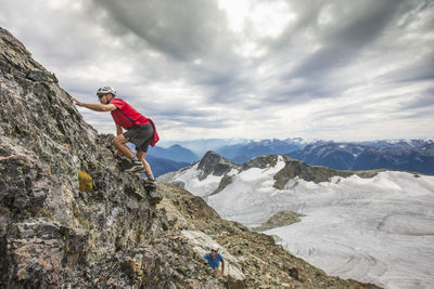 Two climbers scramble up a rocky cliff in the mountains..