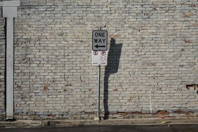 Signboard against brick wall