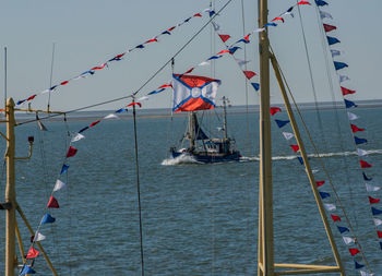 Sailboat hanging on pole by sea against sky