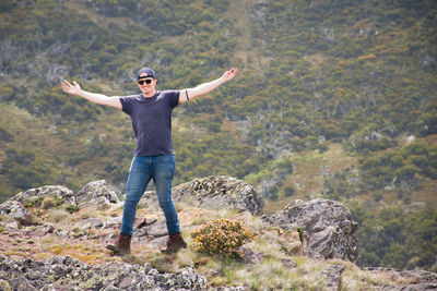 Full length of man with arms outstretched standing on mountain