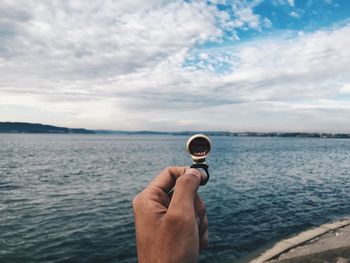 Person holding ice cream in sea against sky