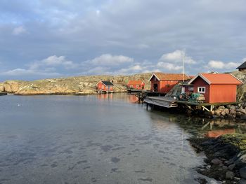 Houses by lake and buildings against sky