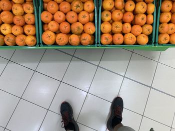 Low section of person standing in front of oranges for sale at market