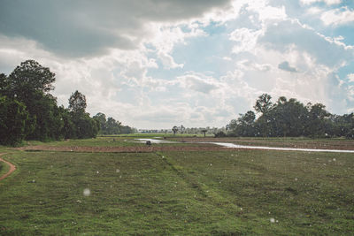 Scenic view of green landscape against cloudy sky