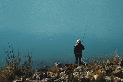 Man fishing in sea against clear sky