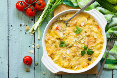 Casserole crumble with red fish, white bread and cheese on the kitchen wooden table.