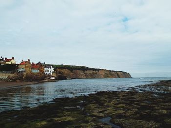 Scenic view of sea by buildings against sky