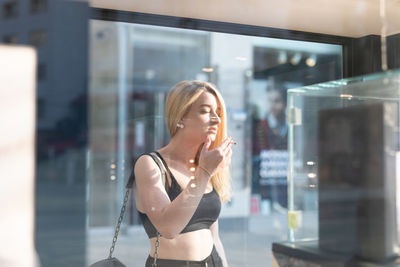 Woman smoking cigarette seen though glass window