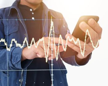 Digital composite image of pulse trace by mature man using smart phone against white background