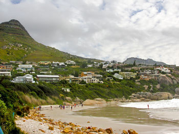 Distant view of people enjoying at clifton beach against cloudy sky