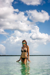 Woman standing in sea against sky