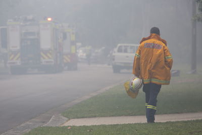 Full length rear view of firefighter walking on sidewalk