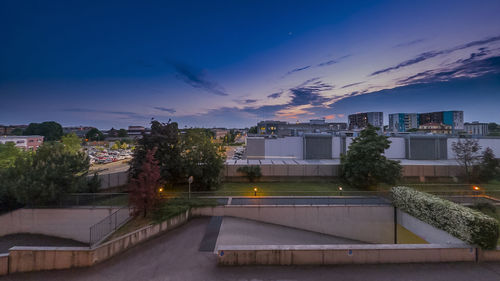 Buildings by swimming pool against sky at sunset