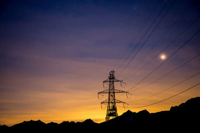 Low angle view of silhouette electricity pylon against sky at sunset