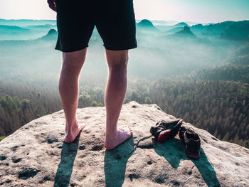 Barefoot slender legs with hairy calves of man runner standing next to removed sweaty running shoes