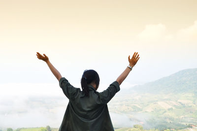 Rear view of friends standing on mountain against sky