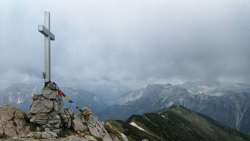 Panoramic view of cross on rock against sky