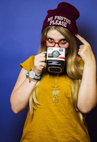 Young woman wearing hat standing against gray background