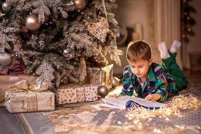 Full length of boy in illuminated christmas tree
