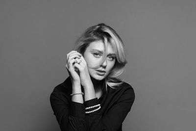Portrait of beautiful young woman against gray background