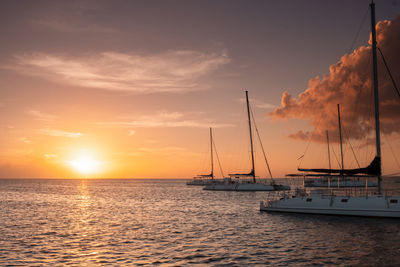 Sailboats in sea against sky during sunset