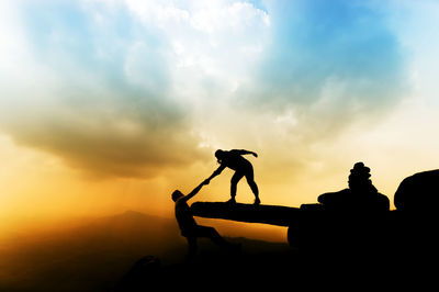 Silhouette of people on mountain at sunset