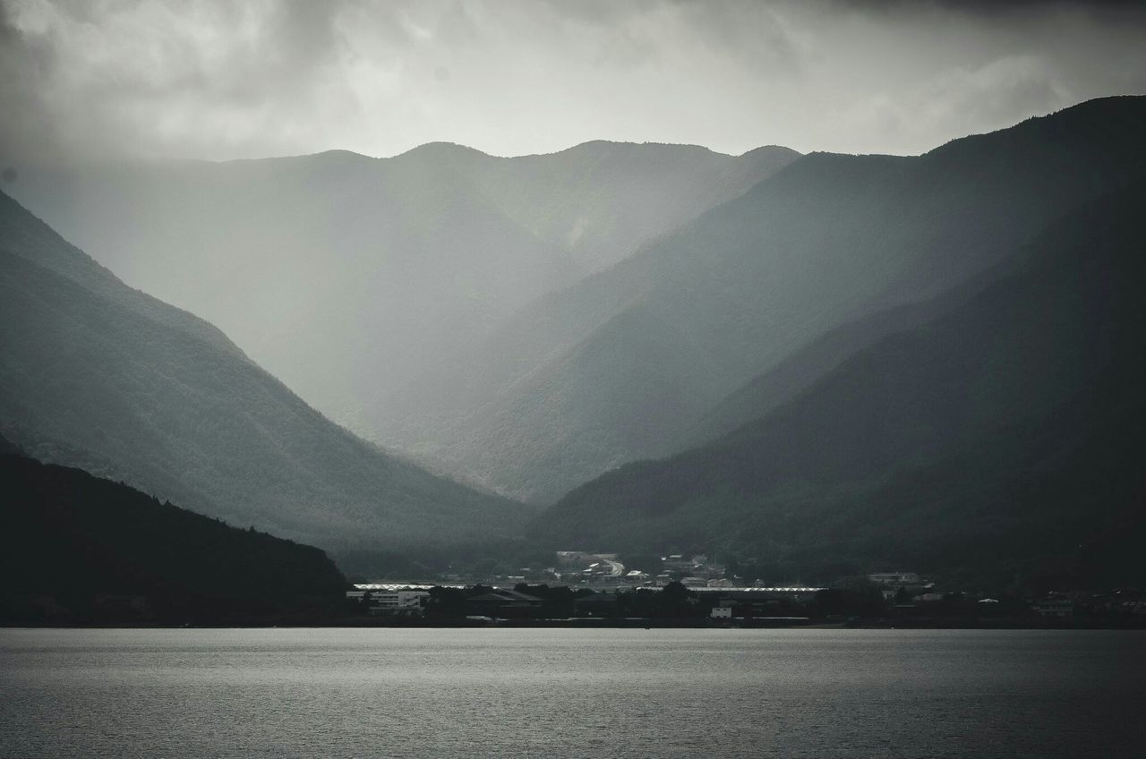 mountain, mountain range, water, scenics, tranquil scene, tranquility, beauty in nature, sky, waterfront, nature, sea, lake, river, landscape, cloud - sky, idyllic, non-urban scene, outdoors, weather, cloudy