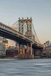 Bridge over river against sky in city