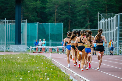 Rear view of people walking on field