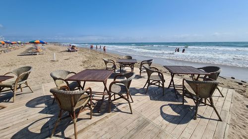 Chairs on table at beach against sky