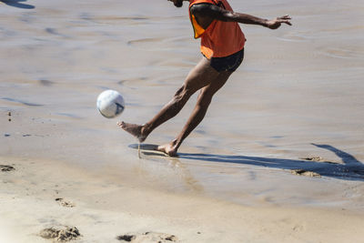 Lower body of a man with a ball on the sand at farol da barra beach in salvador, bahia, brazil.