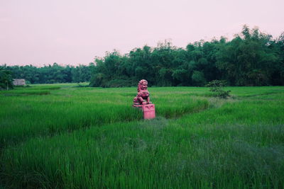 Leo statue standing on field by trees against sky