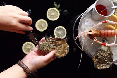 Close-up of person opening oyster