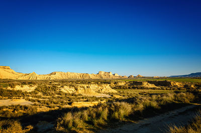 Scenic view of bardenas reales, spain an arid landscape against clear blue sky