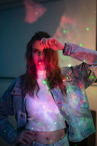 Portrait of woman standing against pink wall