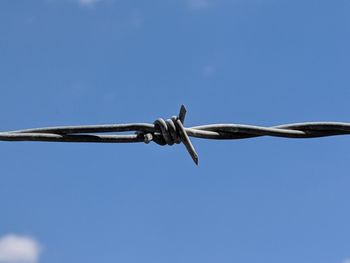 Low angle view of barbed wire against clear blue sky
