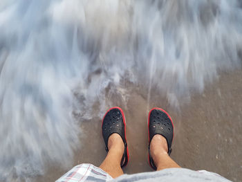 Low section of person standing in water