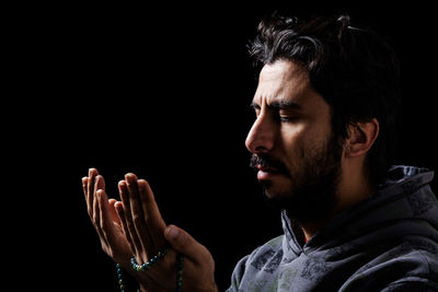 Portrait of man looking away against black background