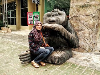 Portrait of woman sitting on monkey statue