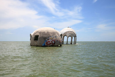 Thatched floating on sea against sky