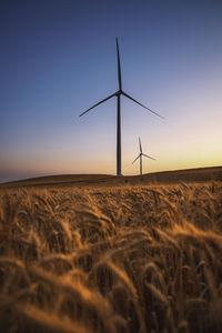 Windmill on field against sky during sunset