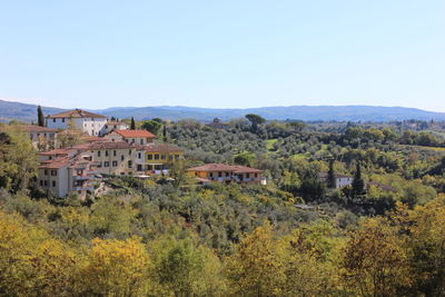 Scenic view of trees and houses against clear sky