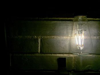 Close-up of illuminated light bulb against black background