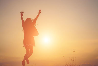 Low angle view of silhouette woman standing against sky during sunset