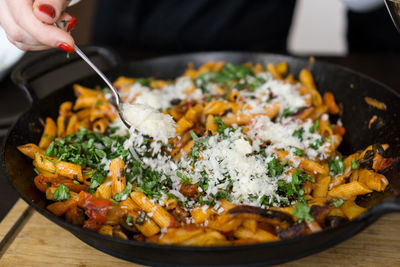 Close-up of hand holding spoon over pasta